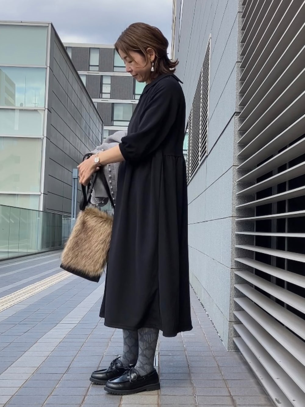 ブラック系のワンピース/ドレス、グレー系のカーディガン/ボレロ、ブラック系のモカシン/デッキシューズを着用したレディースの冬コーディネートの3枚目の写真