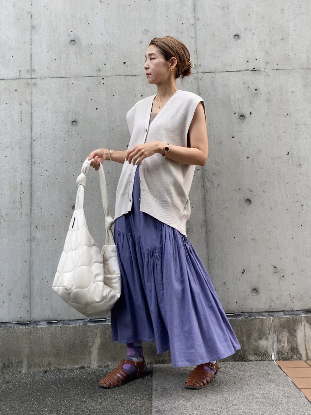 ベージュ系のベスト、グレー系のスカート、ホワイト系のショルダーバッグを着用したレディースの夏コーディネートの3枚目の写真
