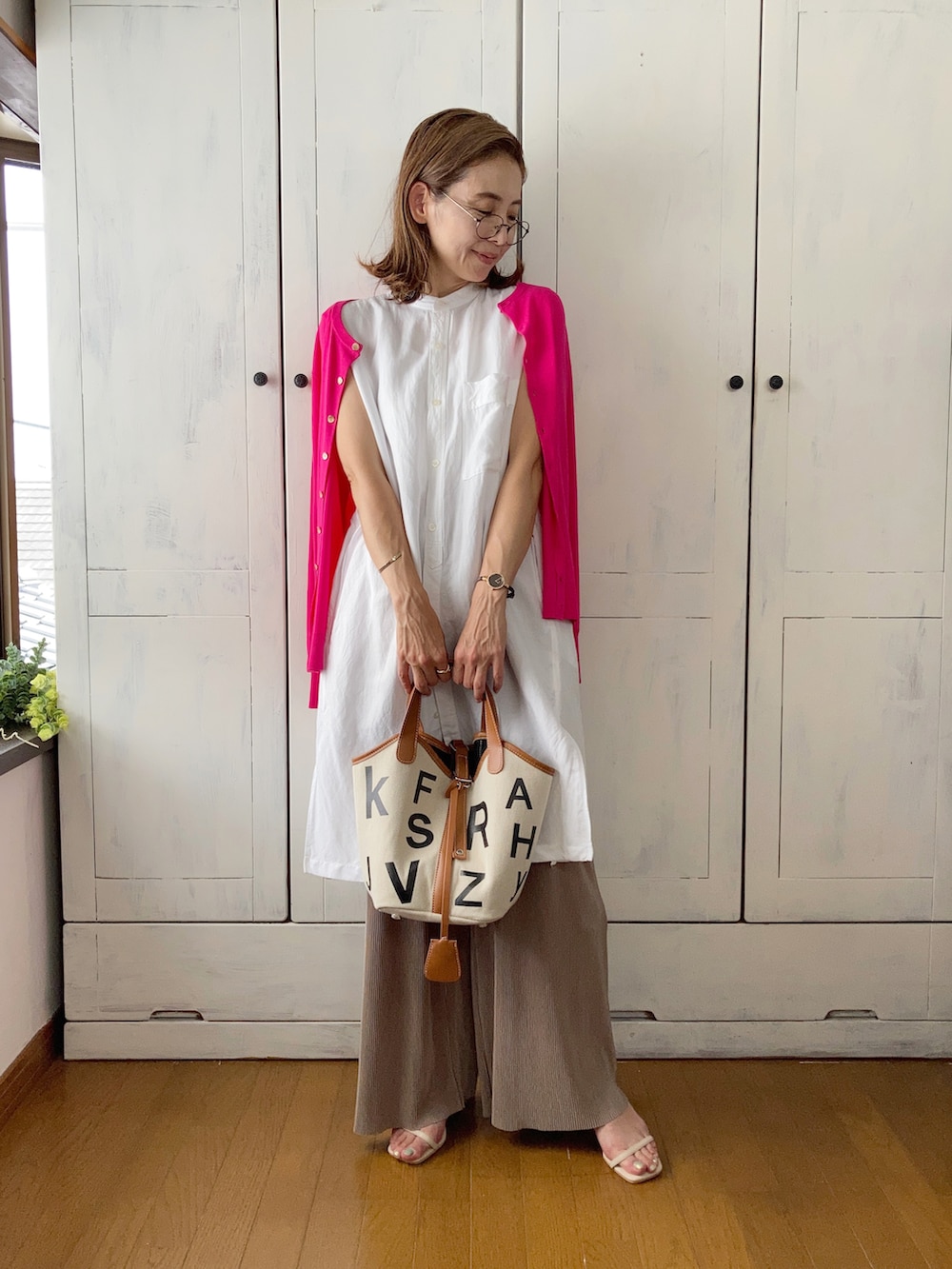 ピンク系のカーディガン/ボレロ、ホワイト系のシャツ/ブラウス、ブラウン系のバッグを着用したレディースの夏コーディネートの2枚目の写真