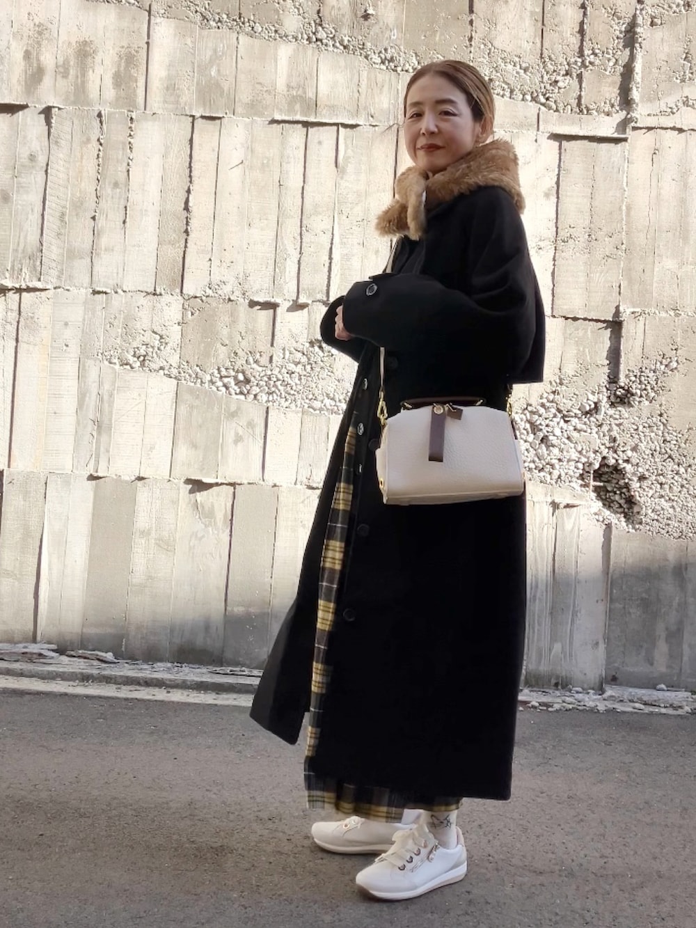 ベージュ系のボストンバッグ、ホワイト系のスニーカー、イエロー系のスカートを着用したレディースの冬コーディネートの4枚目の写真