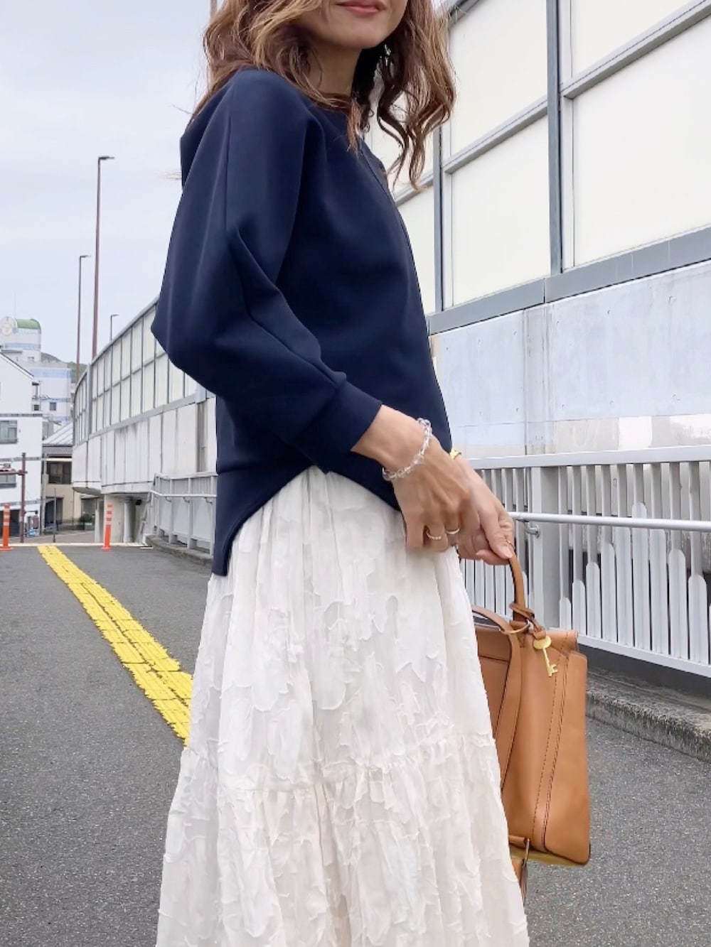 ブルー系のトップス、ブラック系のパンプス、イエロー系のバックパック/リュックを着用したレディースの春コーディネートの2枚目の写真