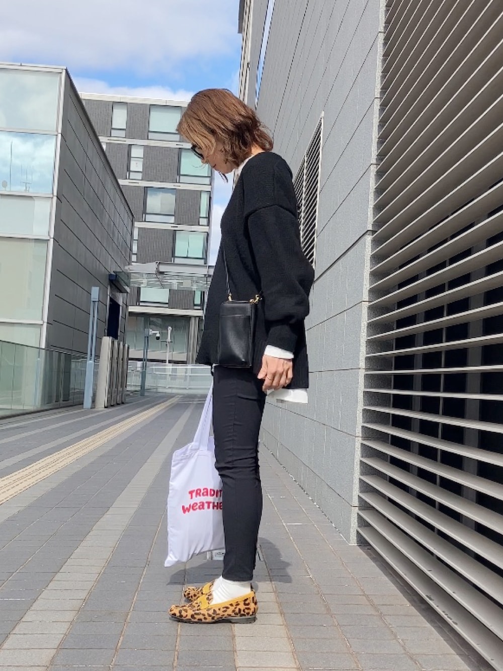 ホワイト系のシャツ/ブラウス、ブラック系のニット/セーター、ブラック系のステンカラーコートを着用したレディースの冬コーディネートの2枚目の写真