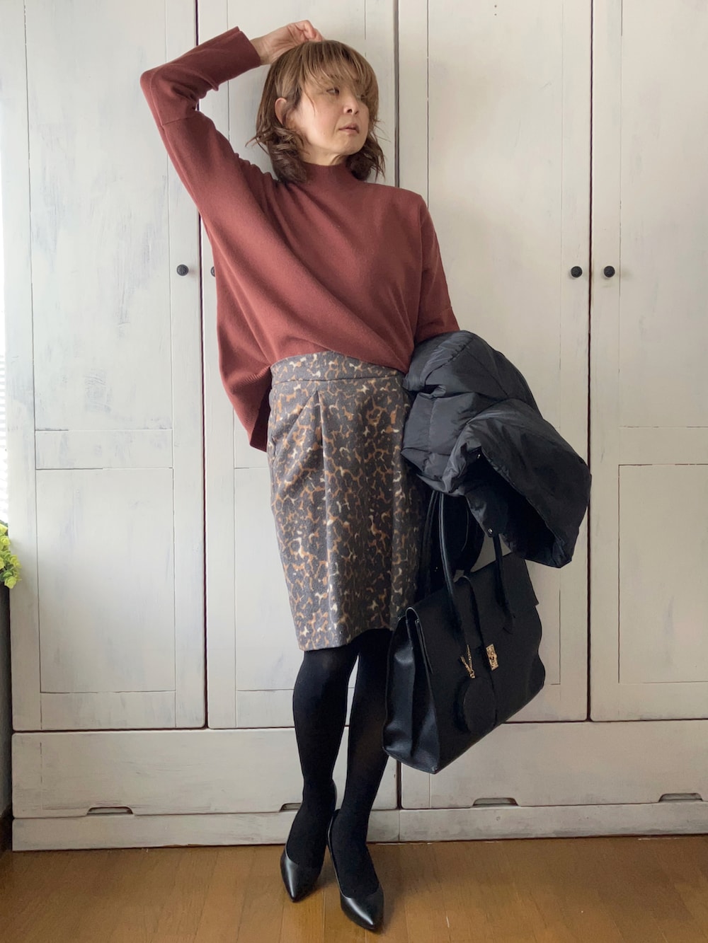 ブラック系のダウンジャケット/コート、ブラウン系のニット/セーター、ブラック系のビジネスバッグを着用したレディースの冬コーディネートの2枚目の写真