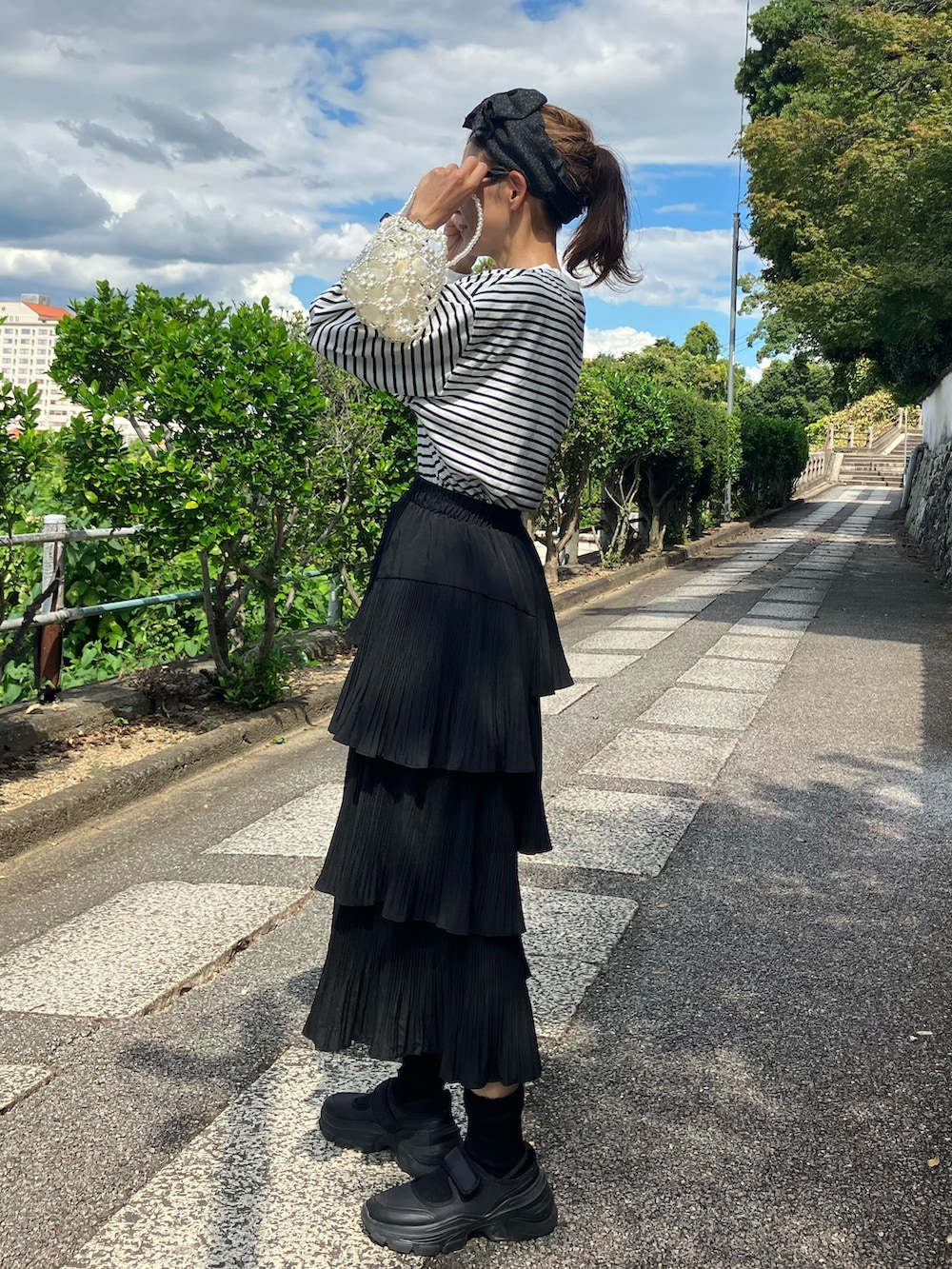 ブラック系のTシャツ/カットソー、ブラック系のスカート、ホワイト系のハンドバッグを着用したレディースの夏コーディネートの3枚目の写真