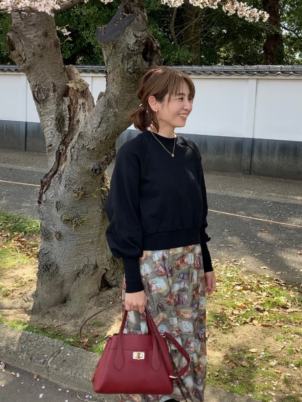 ブラック系のスウェット、レッド系のハンドバッグ、グリーン系のスカートを着用したレディースの春コーディネートの3枚目の写真