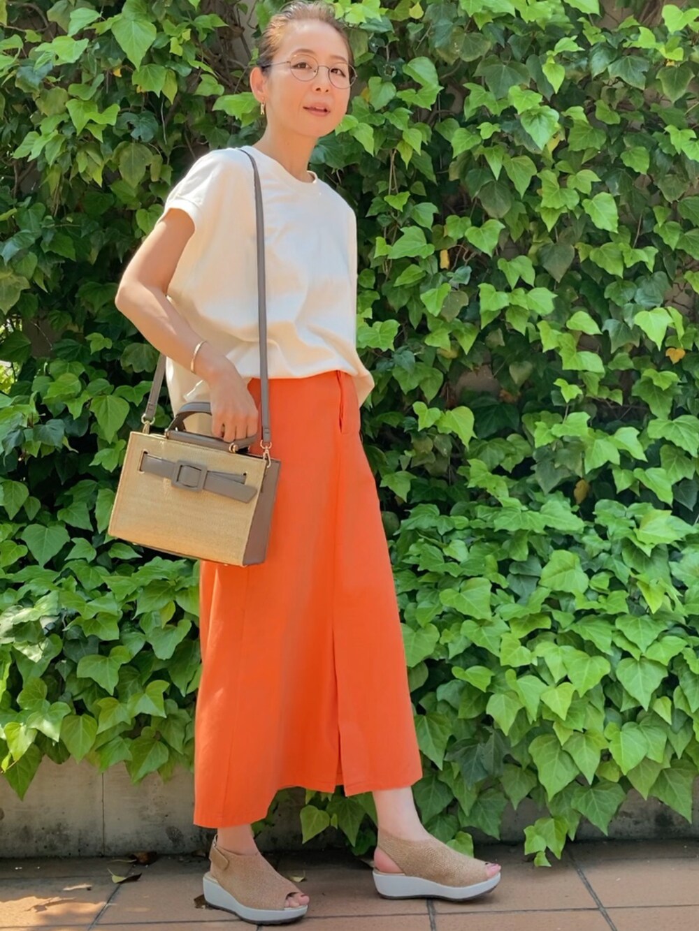 ホワイト系のTシャツ/カットソー、オレンジ系のスカート、グレー系のハンドバッグを着用したレディースの春コーディネートの4枚目の写真