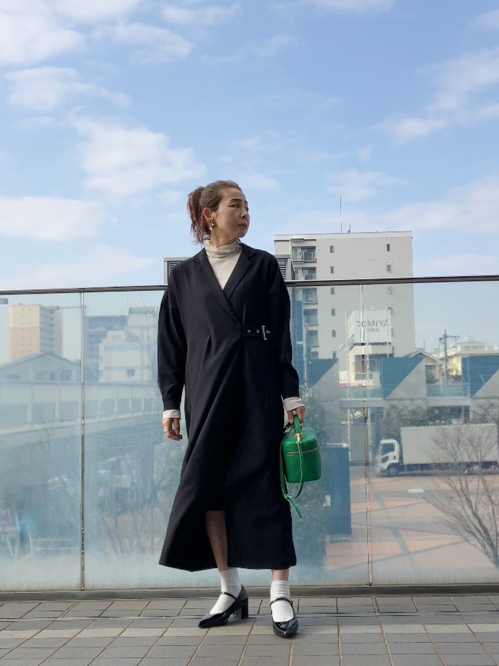 ブラック系のシャツワンピース、ホワイト系のTシャツ/カットソー、グリーン系のショルダーバッグを着用したレディースの冬コーディネートの2枚目の写真