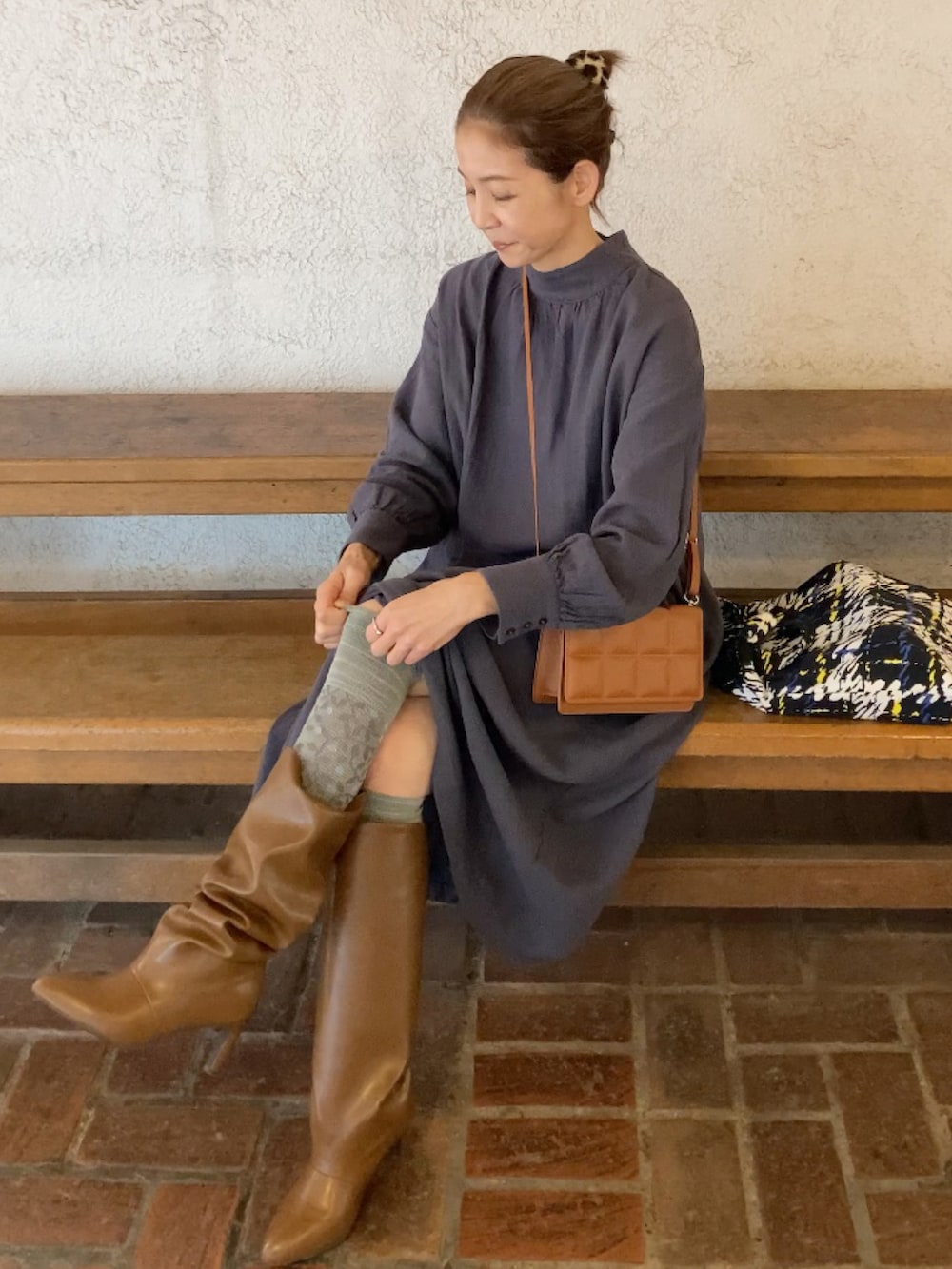 グレー系のワンピース/ドレス、ブラウン系のクラッチバッグ、イエロー系のブーツを着用したレディースの秋コーディネートの5枚目の写真