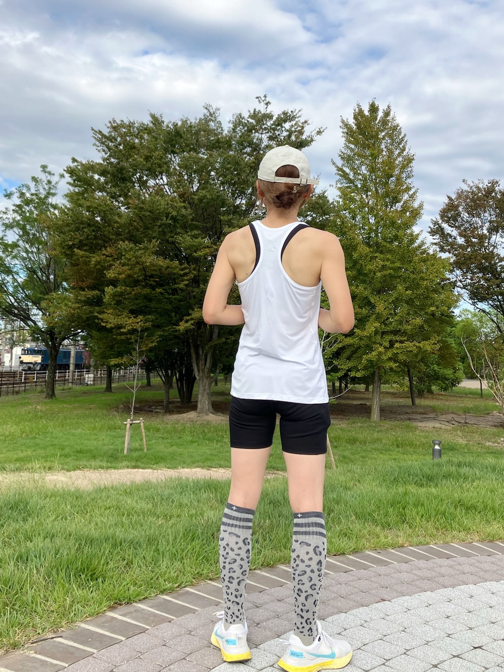 ホワイト系のタンクトップ、ホワイト系のスニーカー、ブラック系のレギンス/スパッツを着用したレディースの秋コーディネートの2枚目の写真