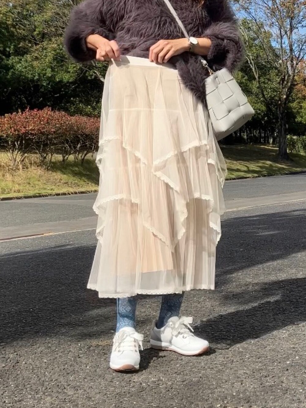 ベージュ系のスカート、グレー系のニット/セーター、グレー系のハンドバッグを着用したレディースの秋コーディネートの4枚目の写真