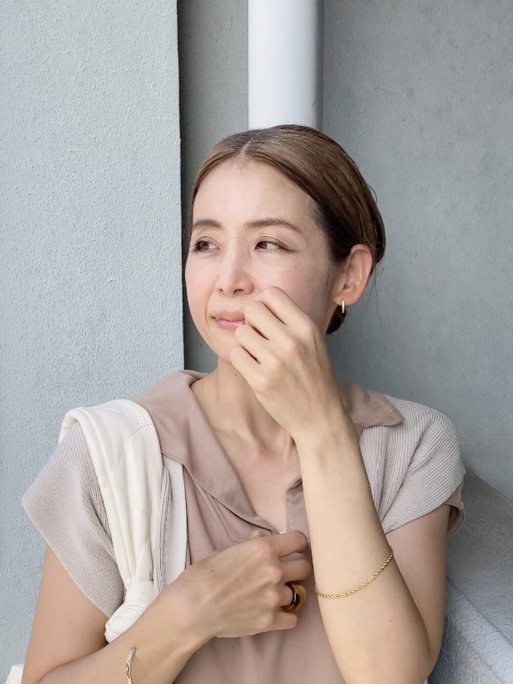 ベージュ系のベスト、ベージュ系のワンピース、ホワイト系のショルダーバッグを着用したレディースの夏コーディネートの2枚目の写真