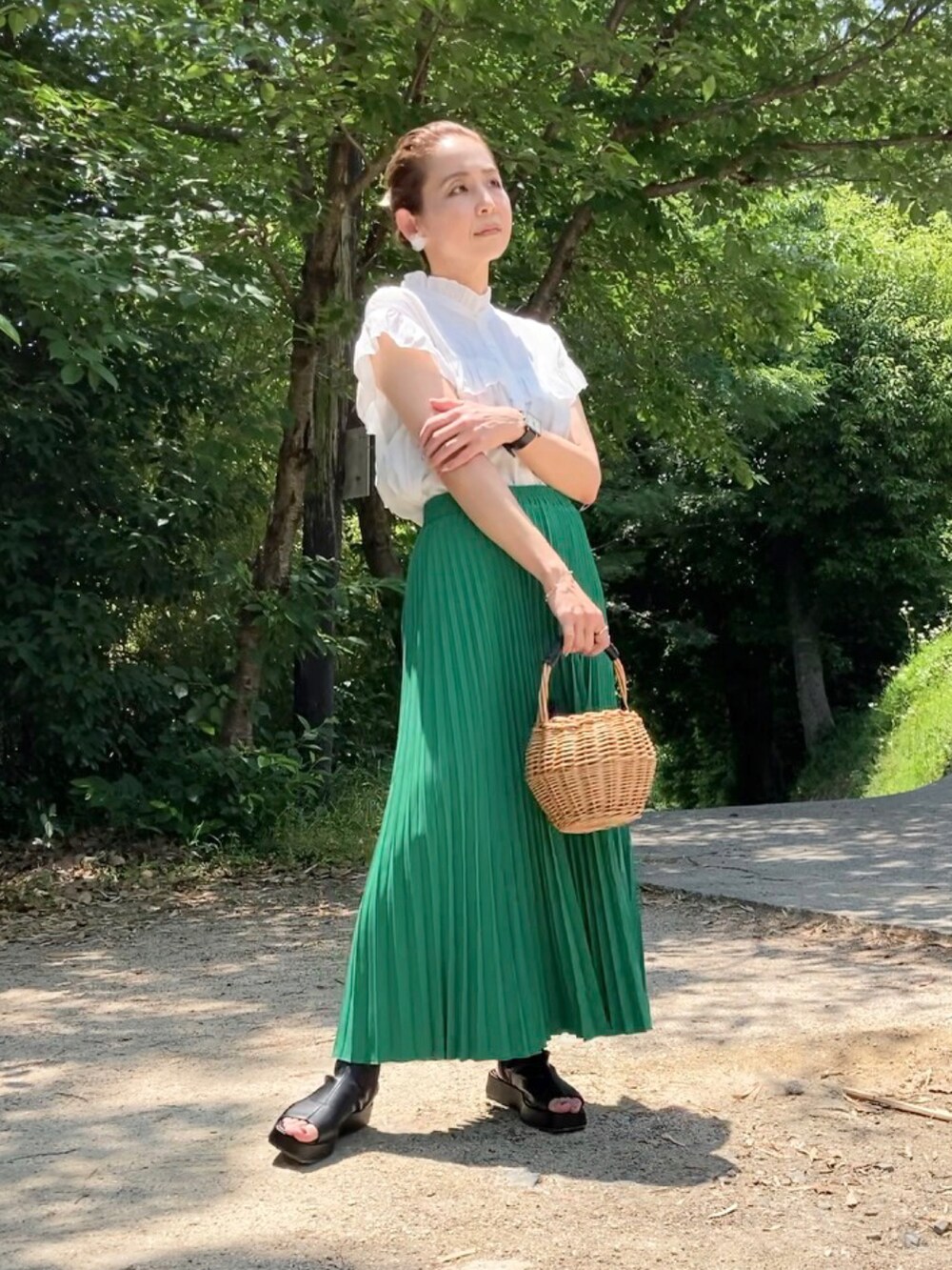 グリーン系のスカート、ホワイト系のシャツ/ブラウス、ブラック系のブーツを着用したレディースの夏コーディネートの2枚目の写真