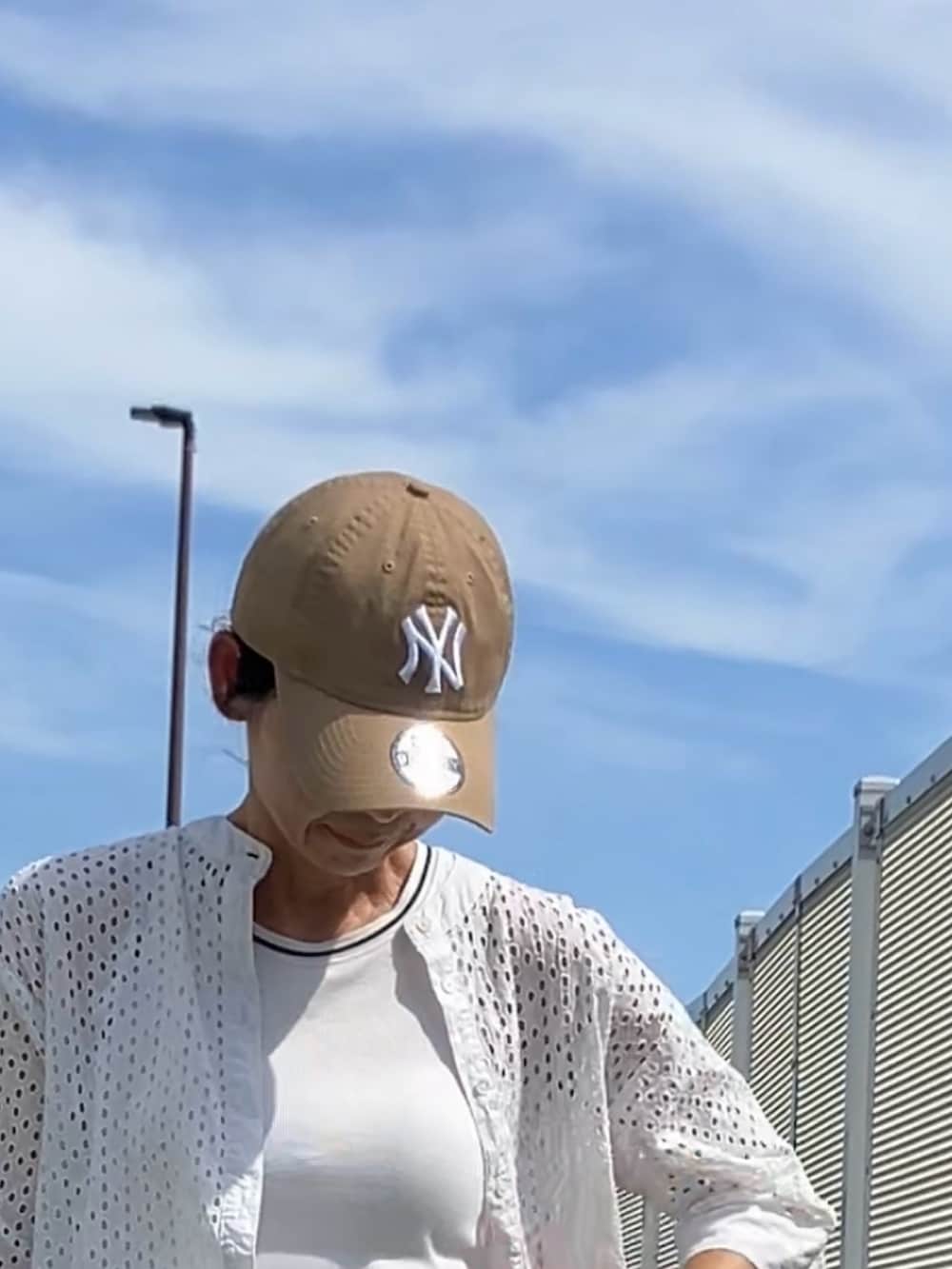 レッド系のバッグ、ベージュ系のキャップを着用したレディースの夏コーディネートの2枚目の写真