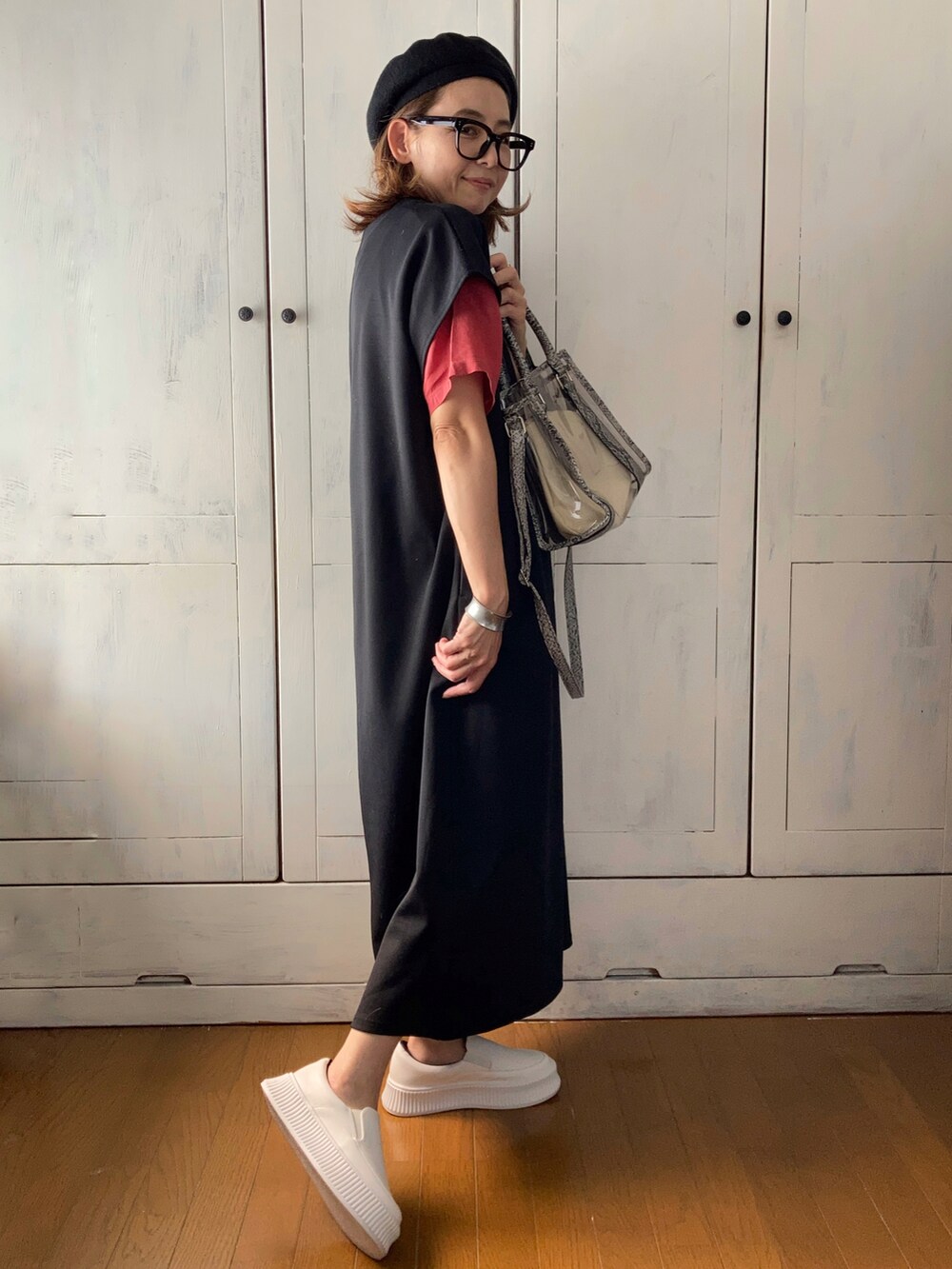 ブラック系のワンピース、レッド系のトップス、ホワイト系のスリッポンを着用したレディースの夏コーディネートの2枚目の写真