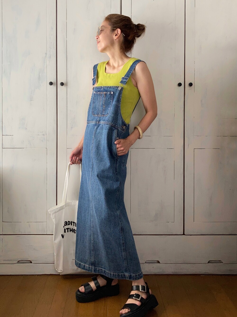 ブルー系のサロペット/オーバーオール、グリーン系のタンクトップ、ホワイト系のトートバッグを着用したレディースの夏コーディネートの2枚目の写真