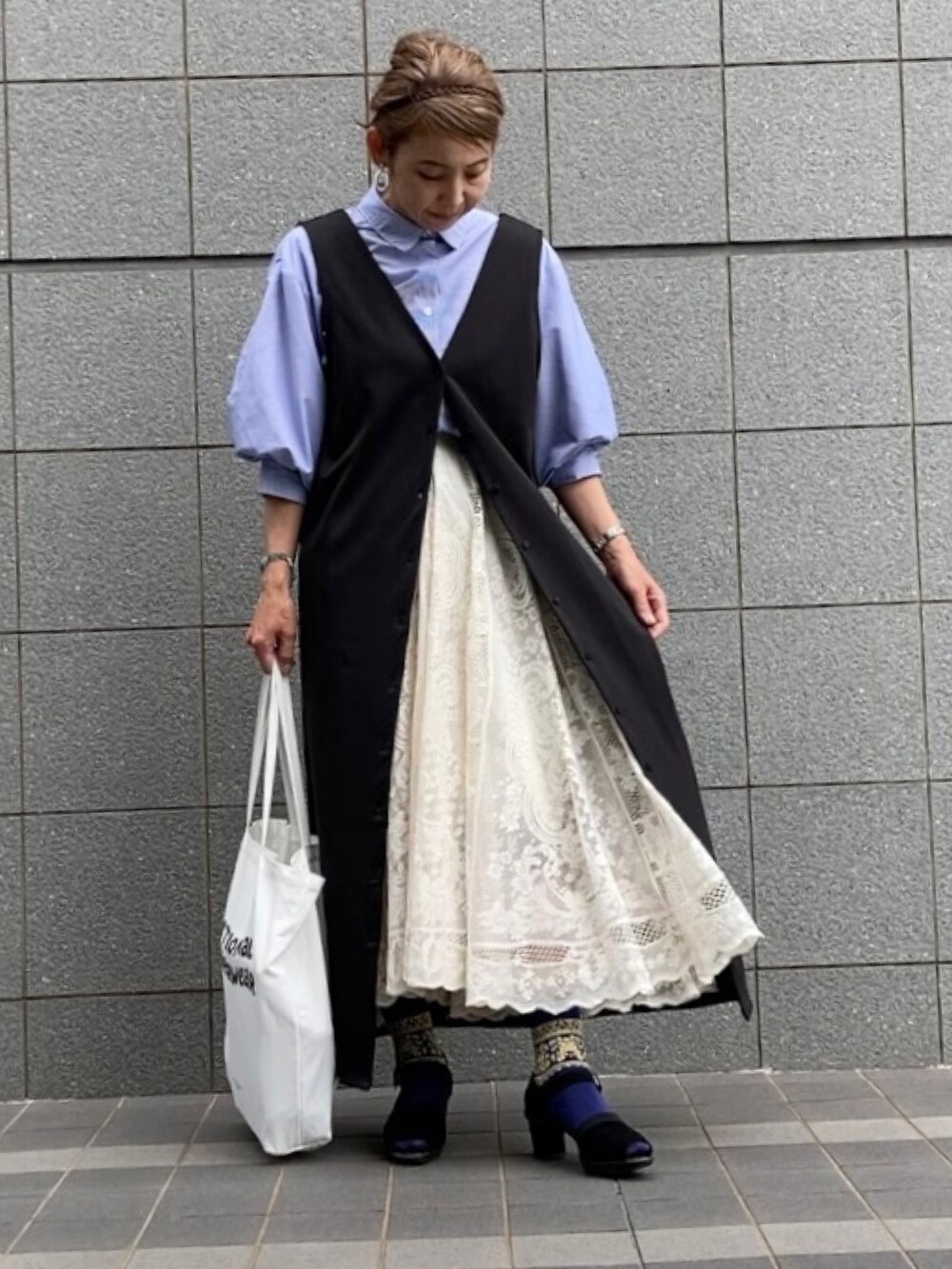 ブラック系のジャンパースカート、ブルー系のその他トップス、ホワイト系のスカートを着用したレディースの春コーディネートの2枚目の写真