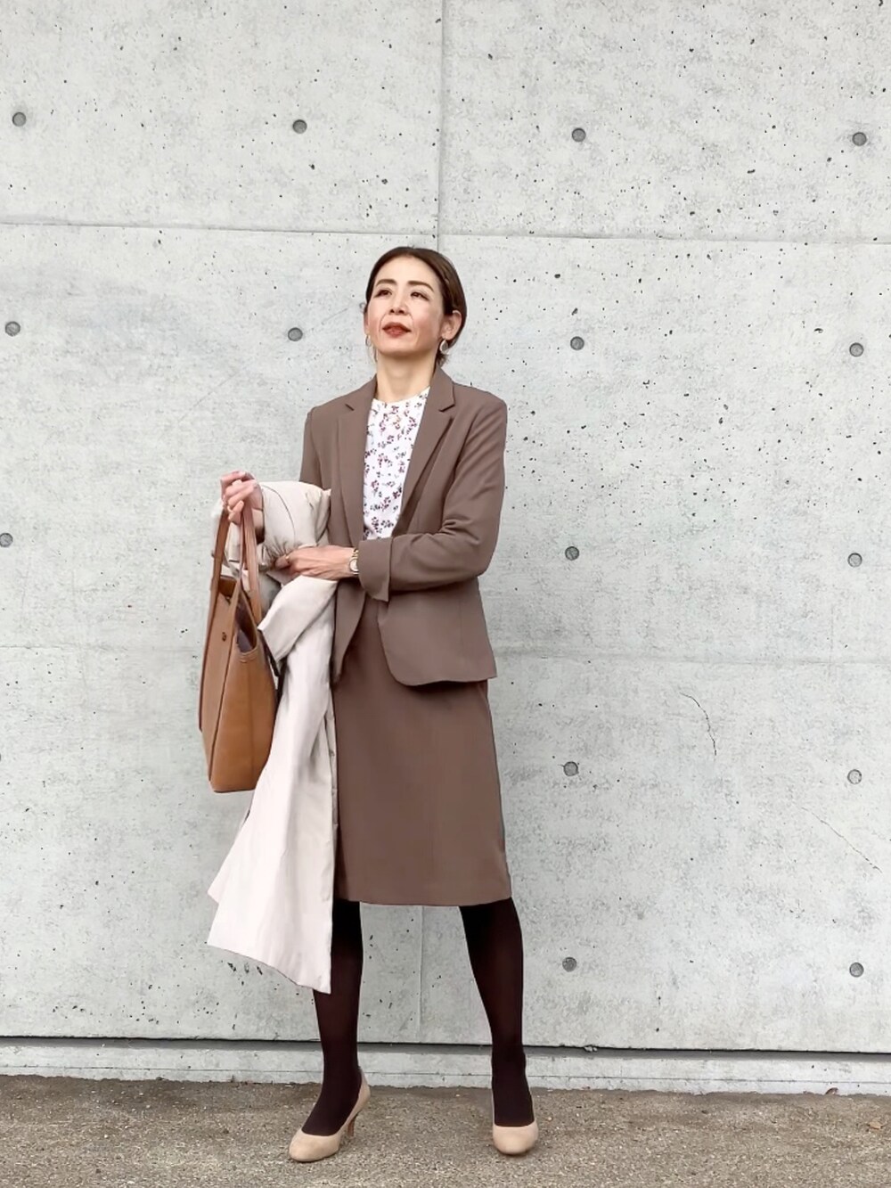 ブラウン系のスーツセット、ブラウン系のバッグ、ベージュ系のシューズを着用したレディースの冬コーディネートの2枚目の写真