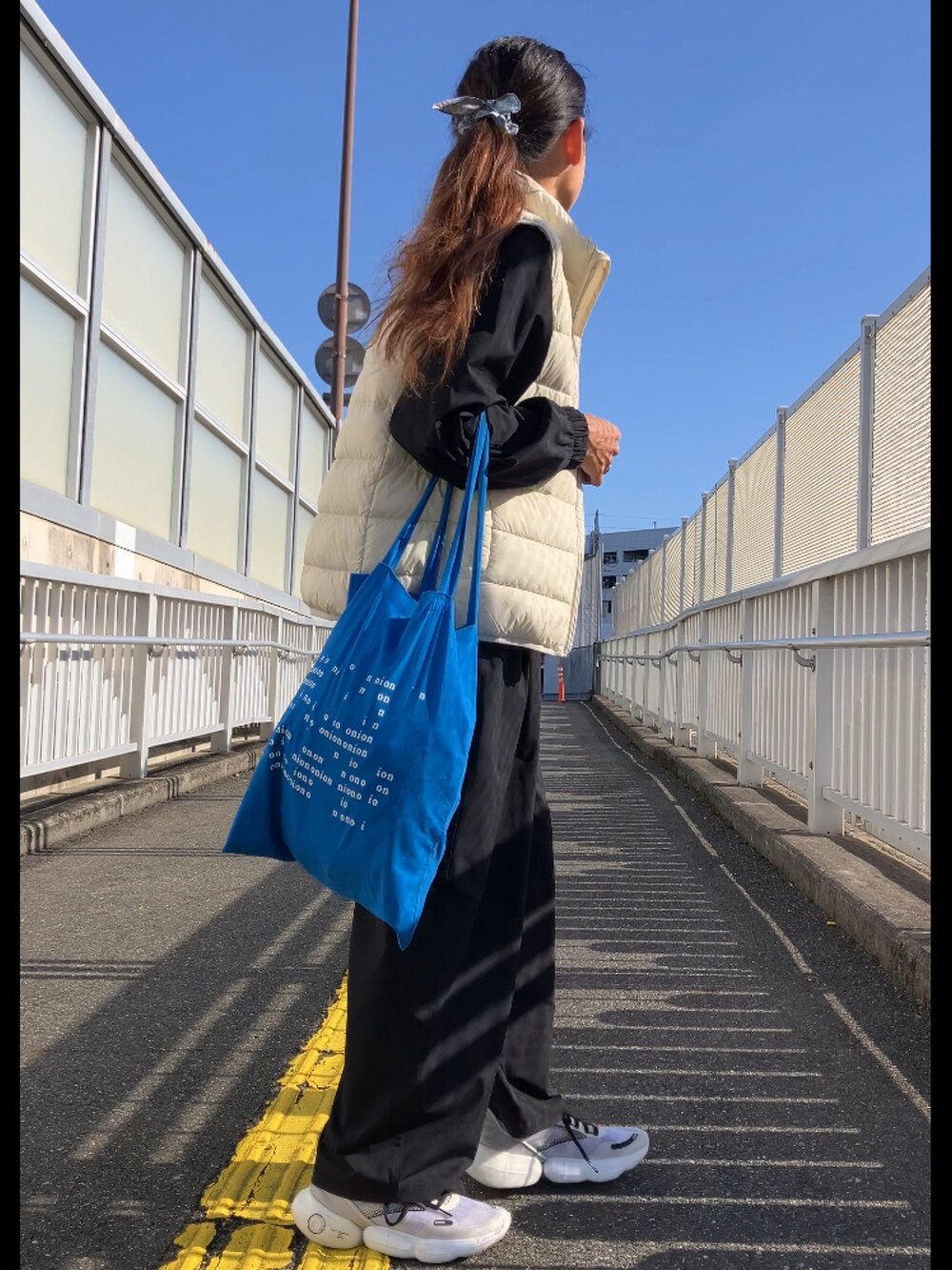ホワイト系のダウンベスト、ブルー系のトートバッグを着用したレディースの秋コーディネートの3枚目の写真