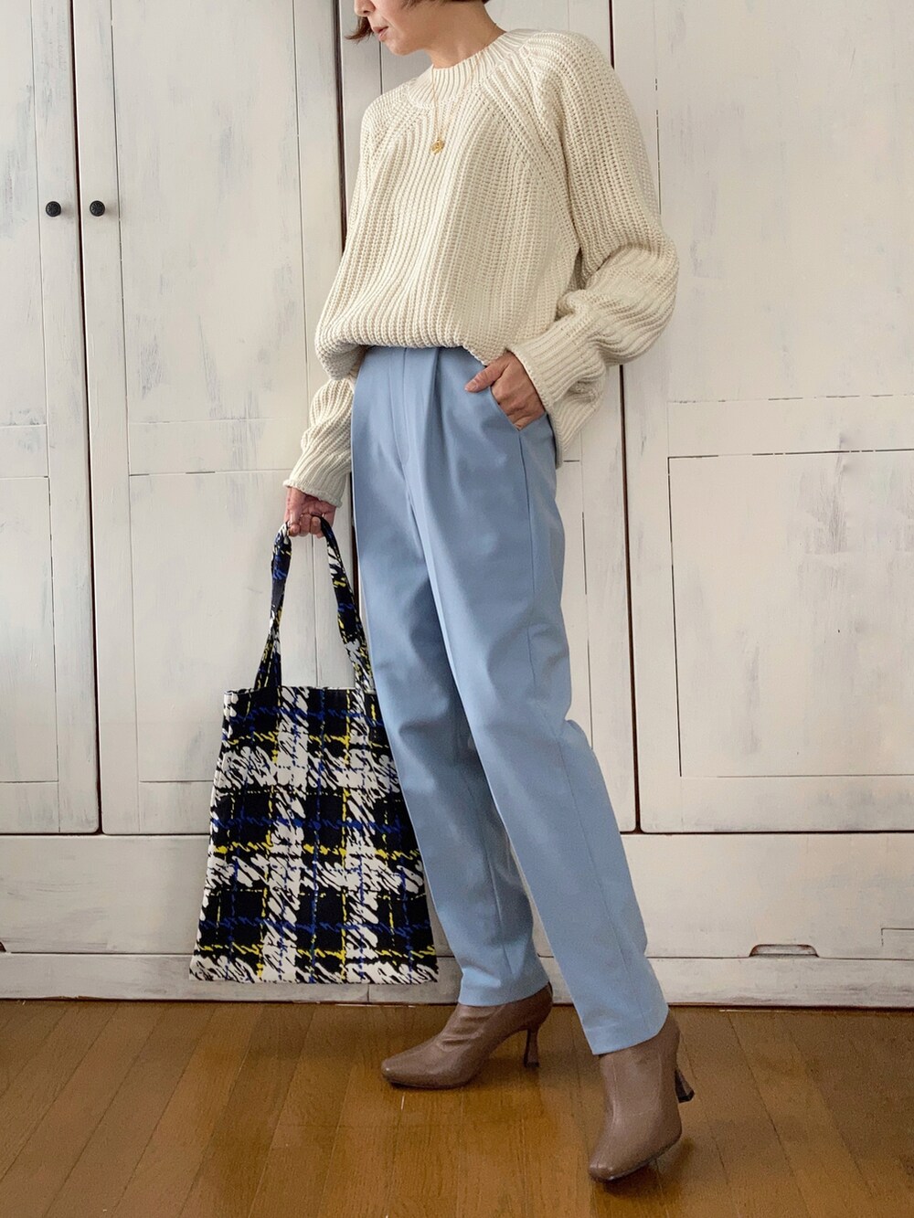 ブラック系のノーカラーコート、ホワイト系のニット/セーター、ブルー系のその他パンツを着用したレディースの秋コーディネートの2枚目の写真