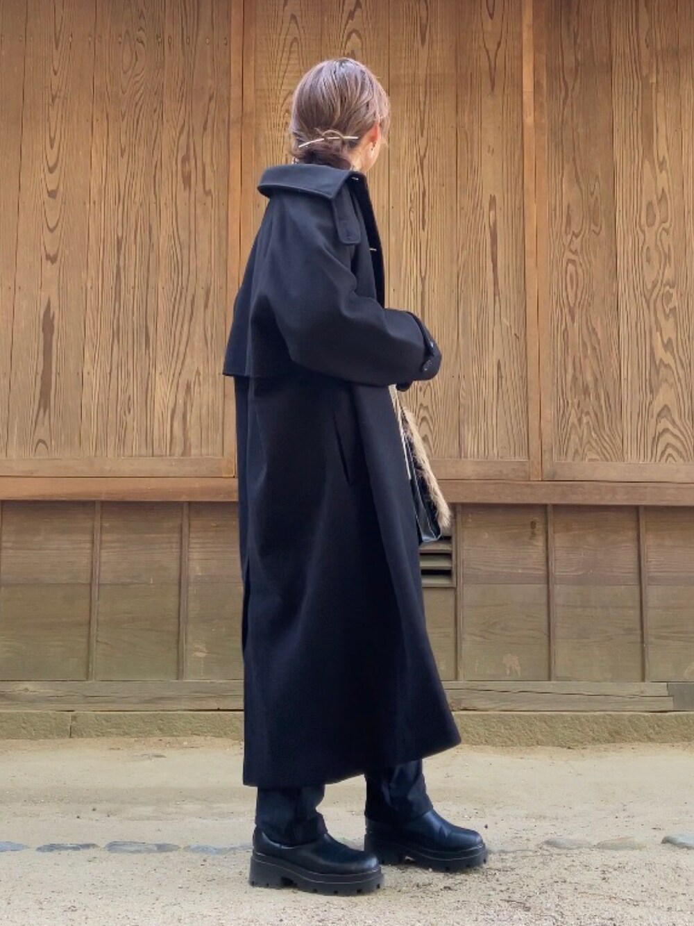 ブラック系のパンツ、ブラック系のステンカラーコート、ベージュ系のニット/セーターを着用したレディースの冬コーディネートの3枚目の写真