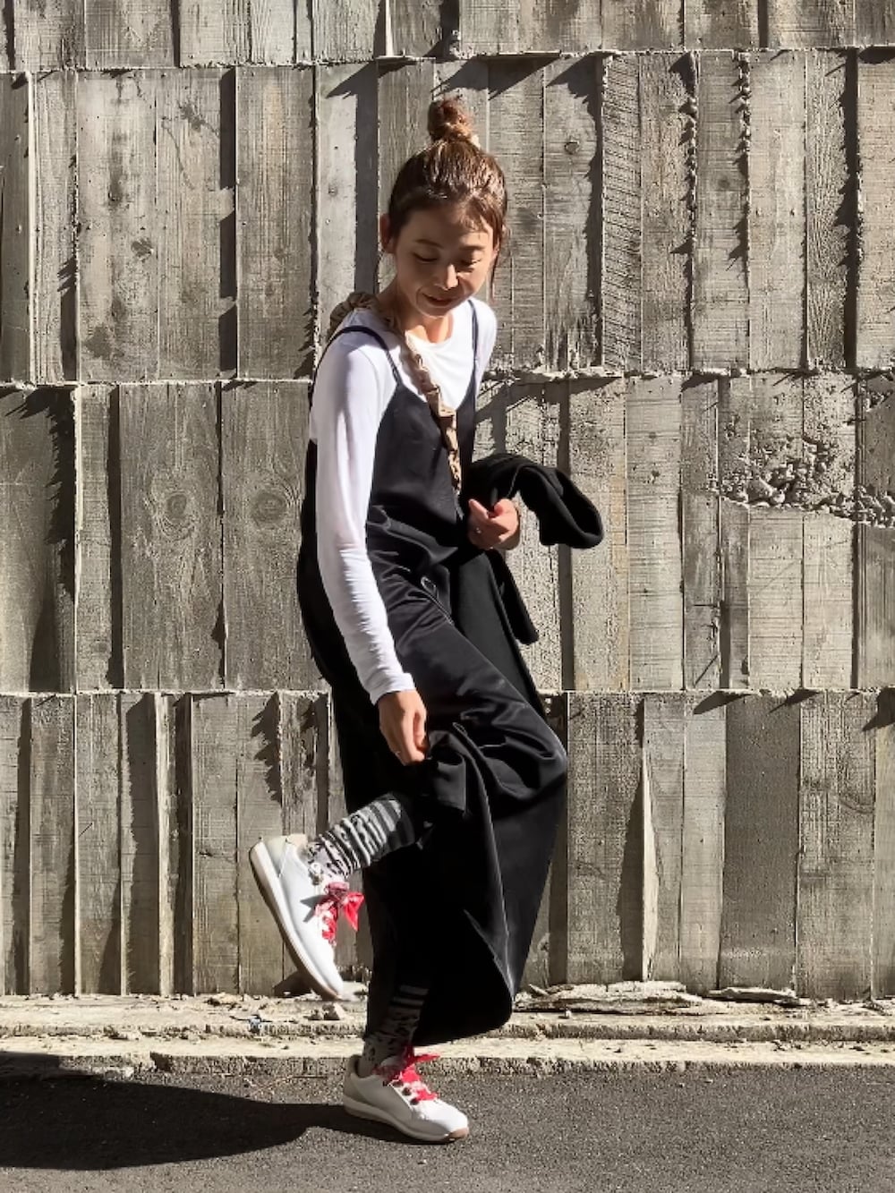 ブラック系のワンピース、オレンジ系のショルダーバッグ、ホワイト系のスニーカーを着用したレディースの冬コーディネートの3枚目の写真