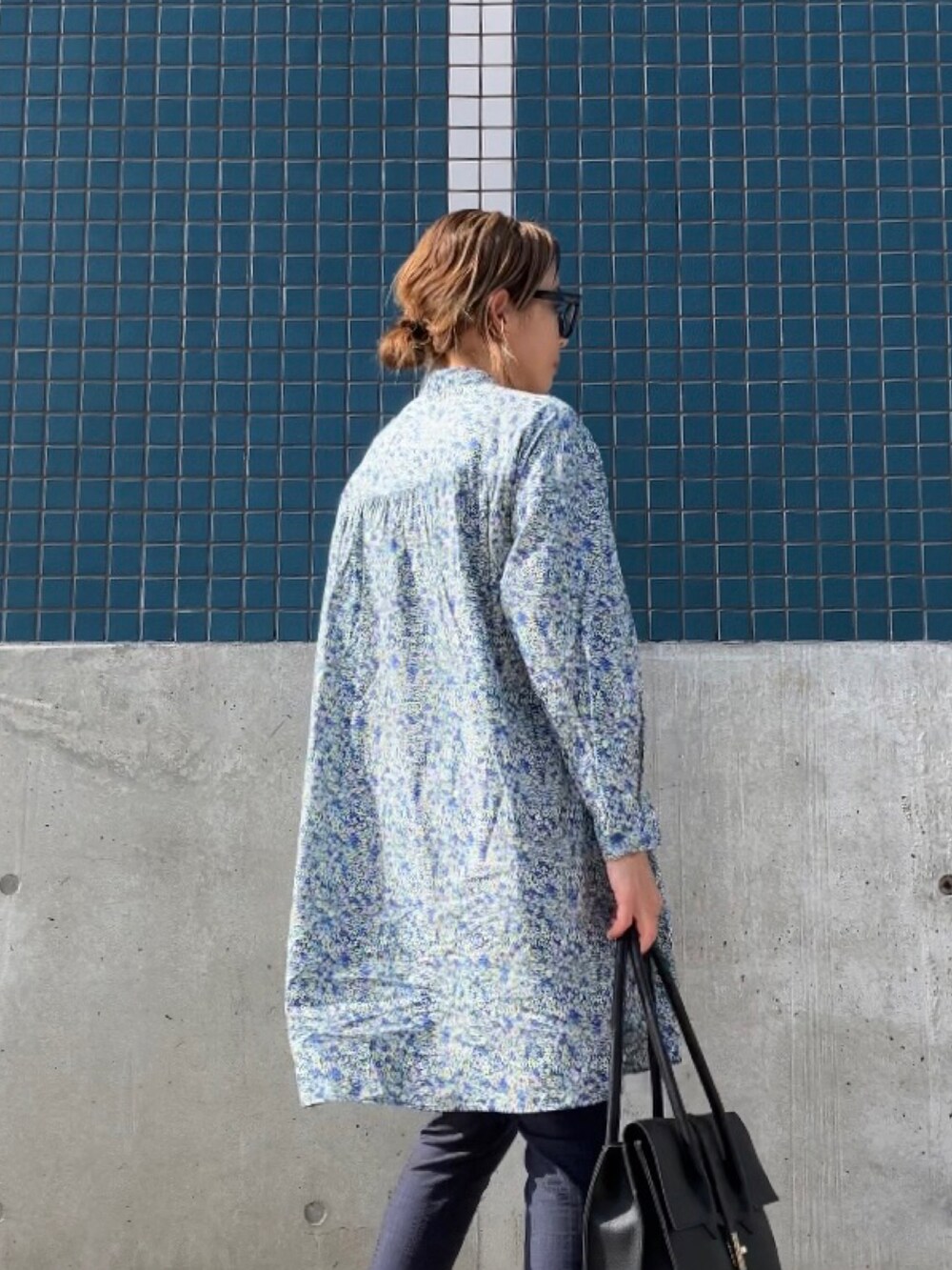 ブルー系のシャツワンピース、ブルー系のパンツ、ブラック系のビジネスバッグを着用したレディースの春コーディネートの3枚目の写真