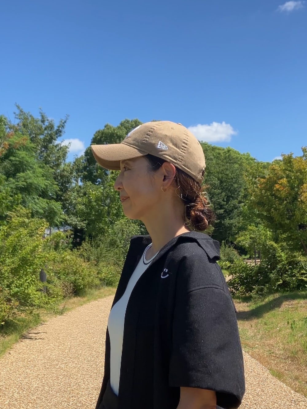 ブラック系のスラックス、イエロー系のサンダル、ベージュ系のキャップを着用したレディースの夏コーディネートの2枚目の写真