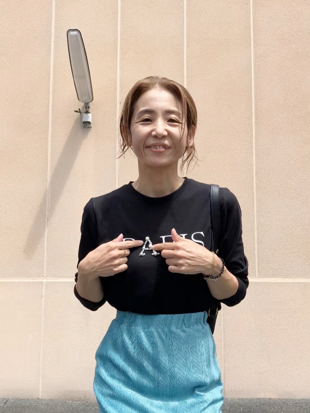 ブラック系のTシャツ/カットソー、ブルー系のスカート、ブラック系のシューズを着用したレディースの夏コーディネートの2枚目の写真