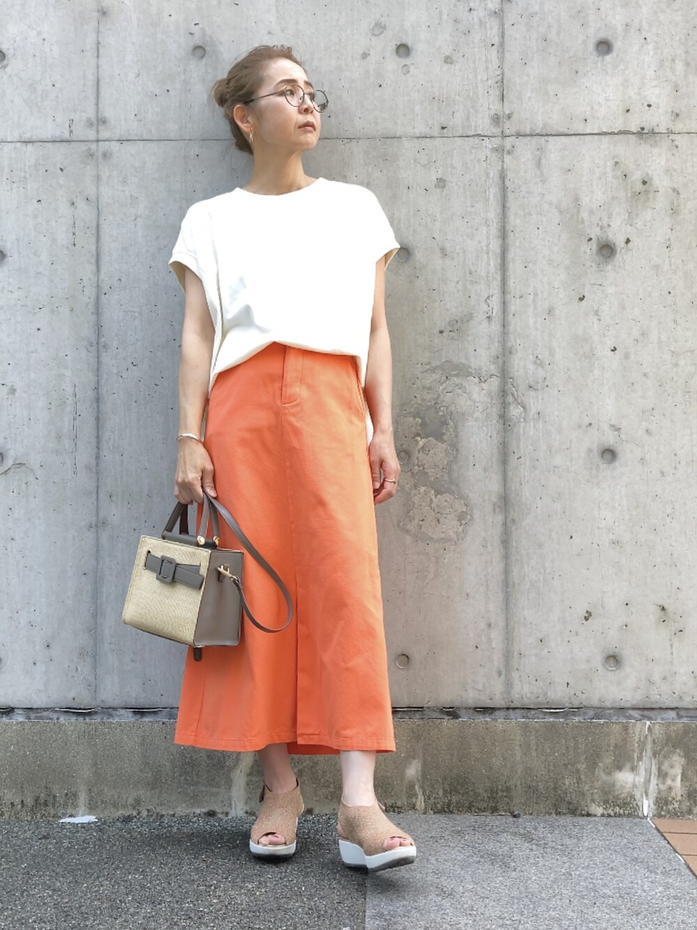 ホワイト系のTシャツ/カットソー、オレンジ系のスカート、グレー系のハンドバッグを着用したレディースの春コーディネートの5枚目の写真