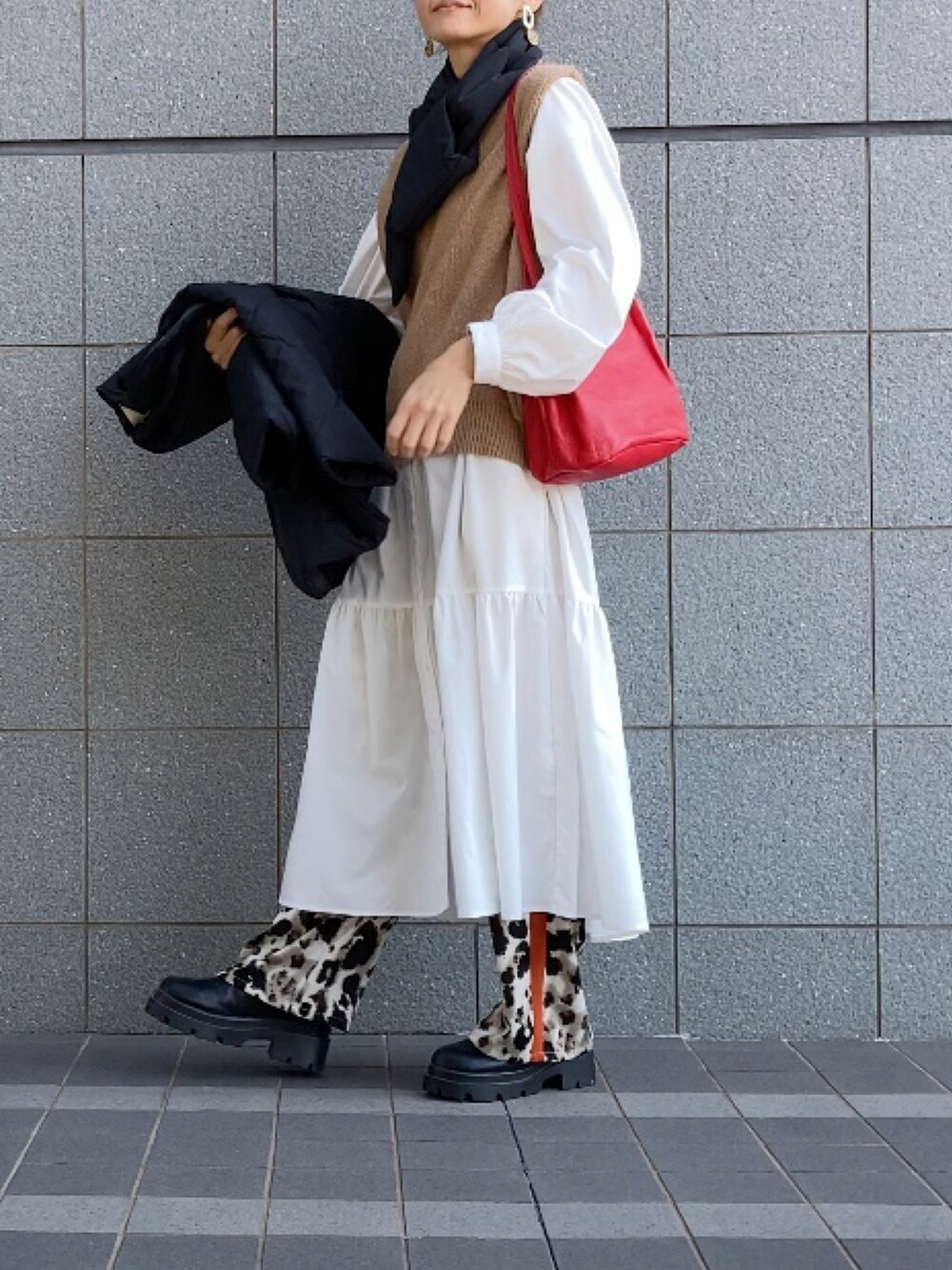 ブラック系のダウンジャケット/コート、ベージュ系のベスト、ホワイト系のワンピース/ドレスを着用したレディースの秋コーディネートの4枚目の写真