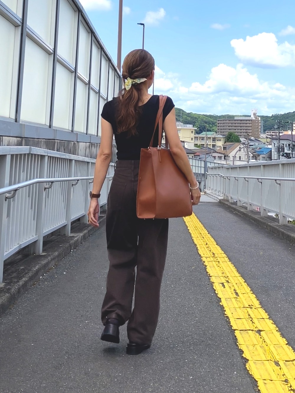 ブラック系のトップス、ブラウン系のデニムパンツ、ブラウン系のトートバッグを着用したレディースの夏コーディネートの3枚目の写真