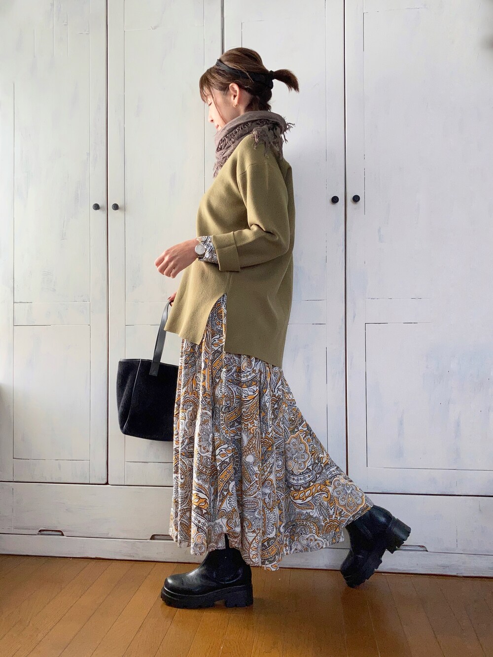 グリーン系のニット/セーター、イエロー系のワンピース、ブラック系のブーツを着用したレディースの秋コーディネートの2枚目の写真