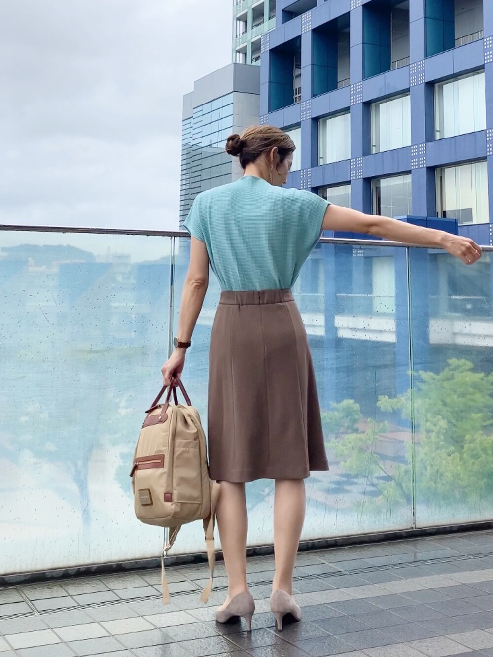 グリーン系のニット/セーター、ブラウン系のスカート、ベージュ系のバックパック/リュックを着用したレディースの夏コーディネートの2枚目の写真