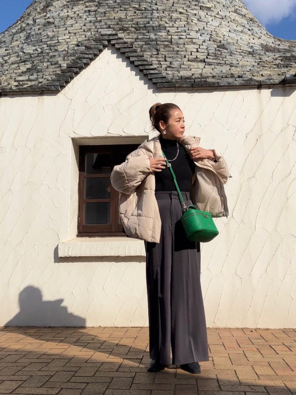 ホワイト系のダウンジャケット/コート、ブラック系のニット/セーター、グレー系のその他パンツを着用したレディースの冬コーディネートの3枚目の写真