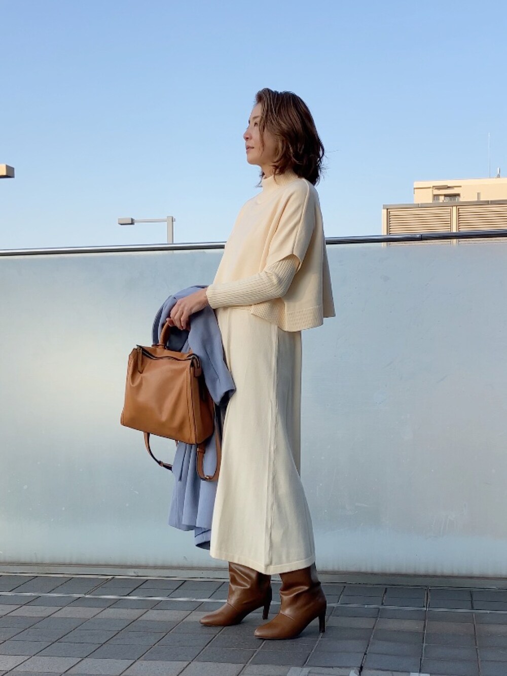 ホワイト系のワンピース、ブルー系のチェスターコート、イエロー系のバックパック/リュックを着用したレディースの冬コーディネートの3枚目の写真