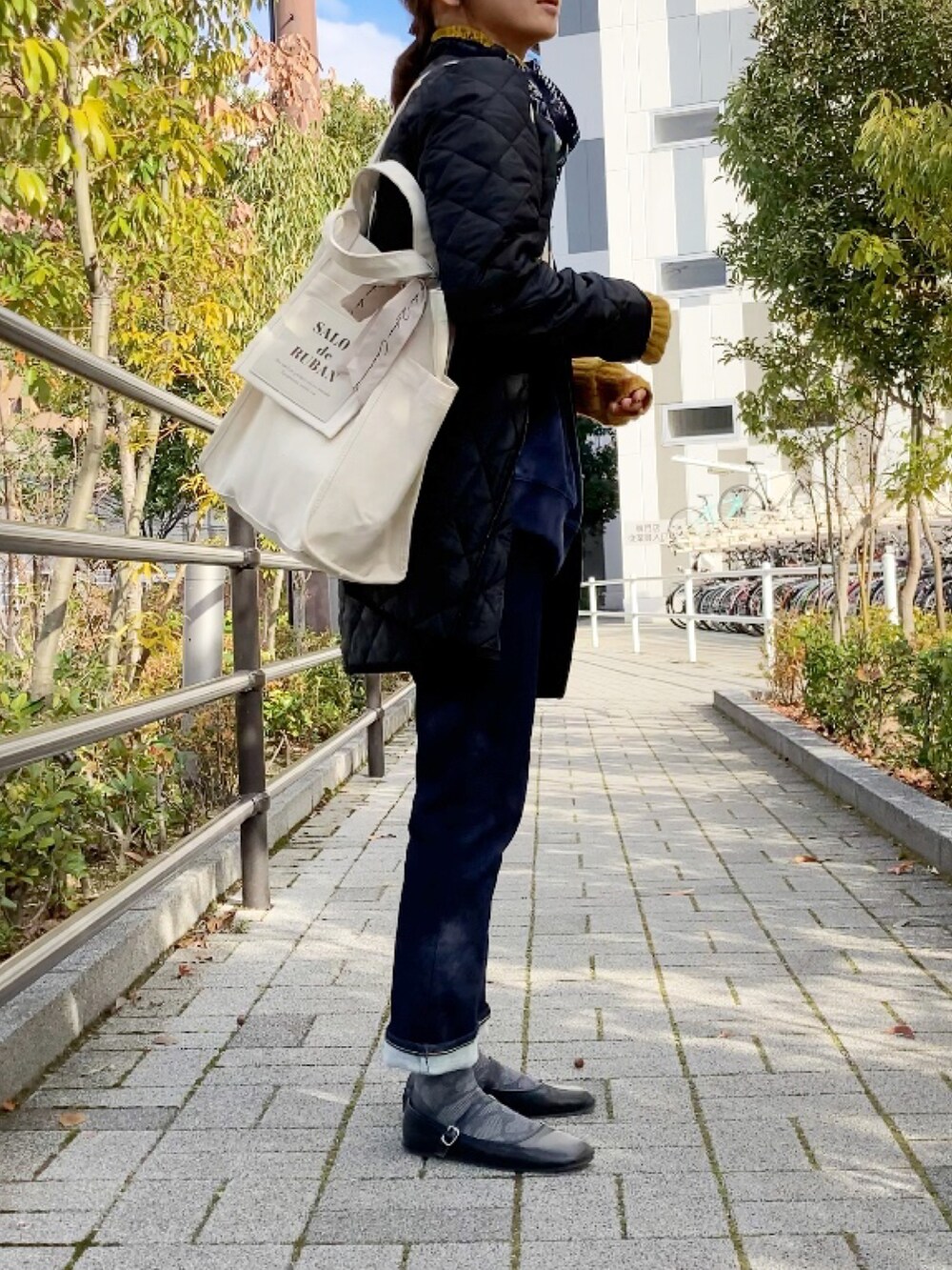 ブラック系のその他アウター、ホワイト系のトートバッグ、ブルー系のデニムパンツを着用したレディースの冬コーディネートの2枚目の写真