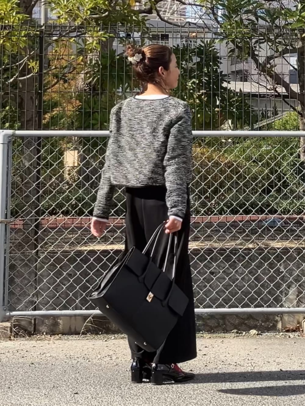 ブラック系のノーカラージャケット、ブラック系のジャンパースカート、ホワイト系のTシャツ/カットソーを着用したレディースの冬コーディネートの2枚目の写真