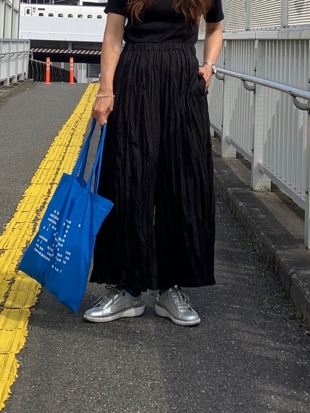 ブラック系のパンツ、ブラック系のTシャツ/カットソー、ブルー系のキャップを着用したレディースの夏コーディネートの3枚目の写真