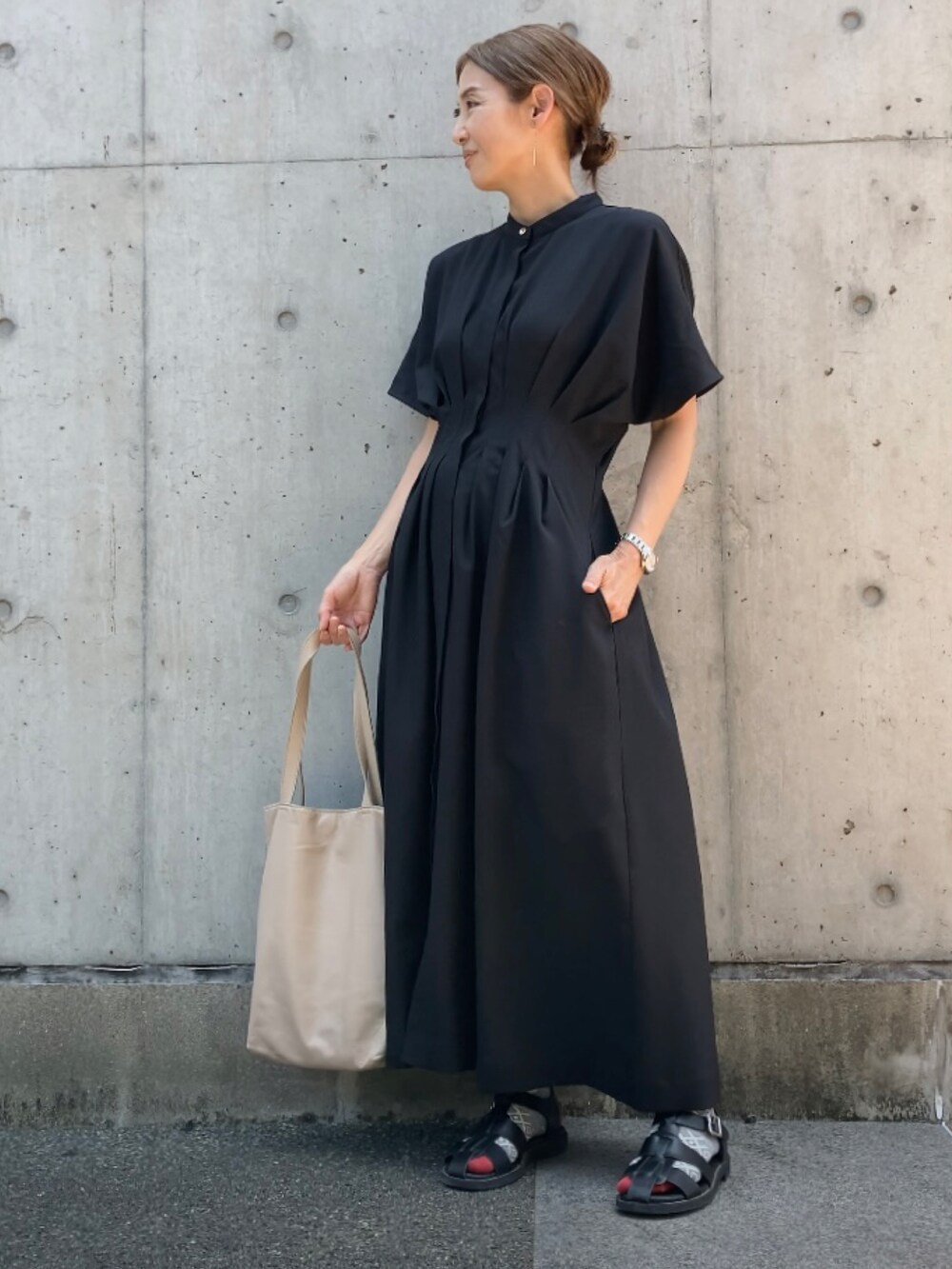ブラック系のワンピース、ベージュ系のトートバッグ、ブラック系のサンダルを着用したレディースの夏コーディネートの2枚目の写真