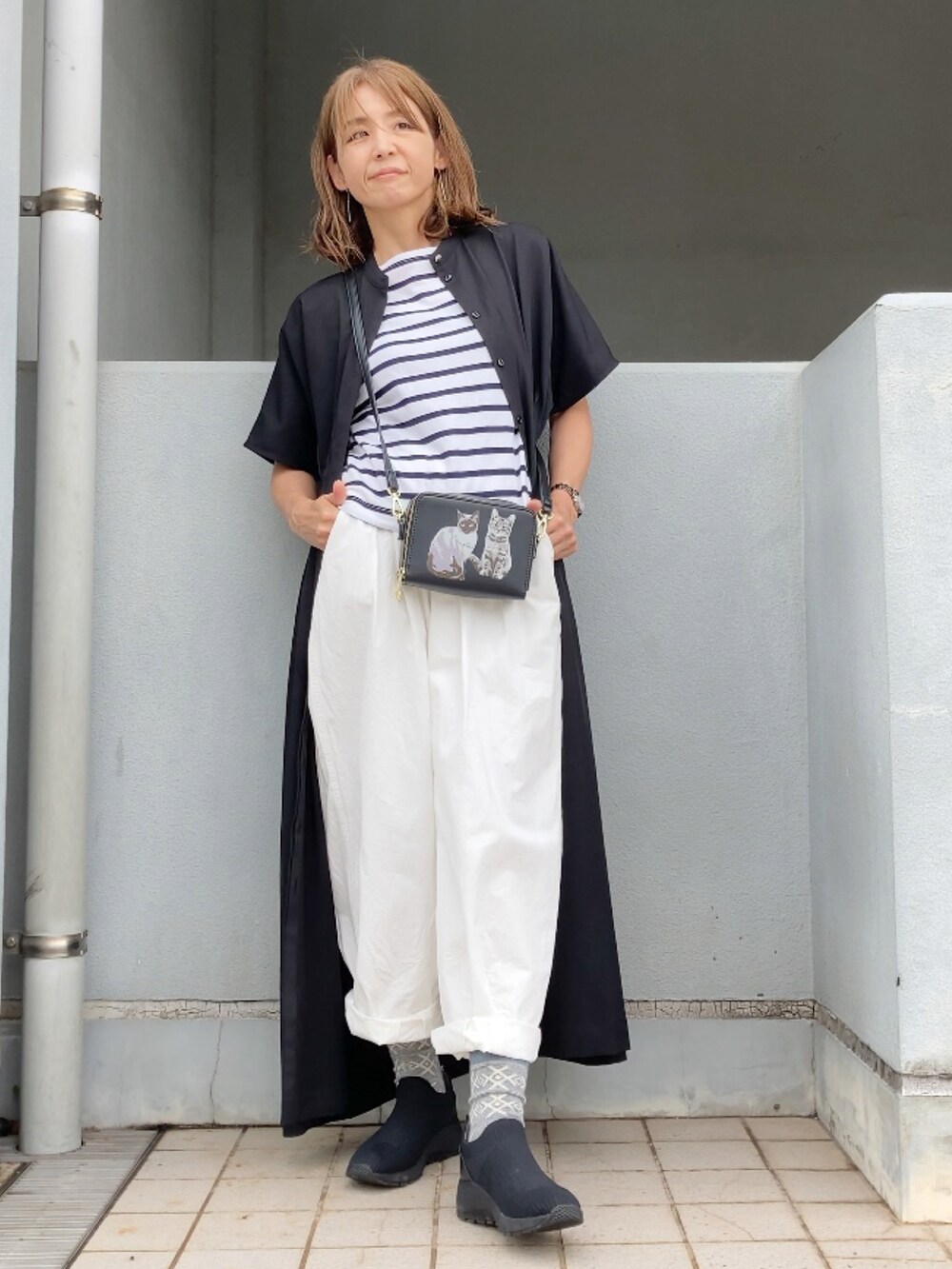 ブラック系のワンピース、ホワイト系のチノパンツ、ブラック系のシューズを着用したレディースの夏コーディネートの3枚目の写真