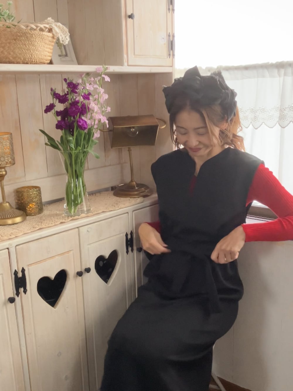 ブラック系のジャンパースカート、ブラック系のレッグウェア、ブラック系のヘアバンドを着用したレディースの冬コーディネートの3枚目の写真