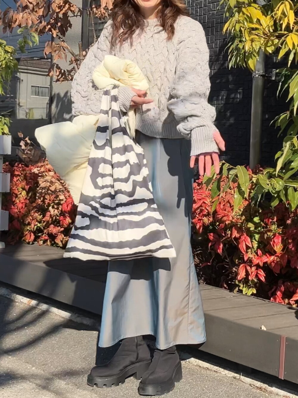 ベージュ系のニット/セーター、グリーン系のスカート、ホワイト系のダウンベストを着用したレディースの冬コーディネートの3枚目の写真