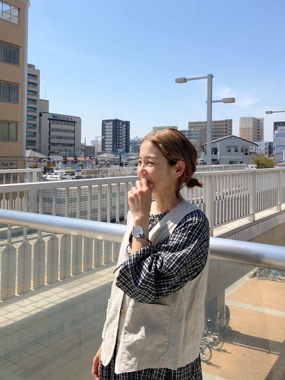 ベージュ系のベスト、ブルー系のデニムジャケット、ブラック系のワンピースを着用したレディースの春コーディネートの2枚目の写真