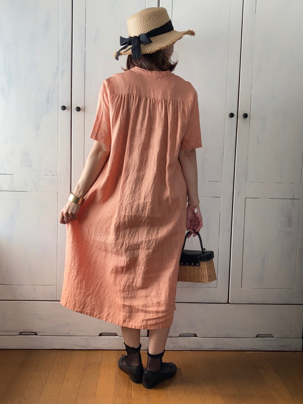 オレンジ系のワンピース/ドレス、ブラウン系のかごバッグ、ブラック系のバレエシューズを着用したレディースの夏コーディネートの2枚目の写真