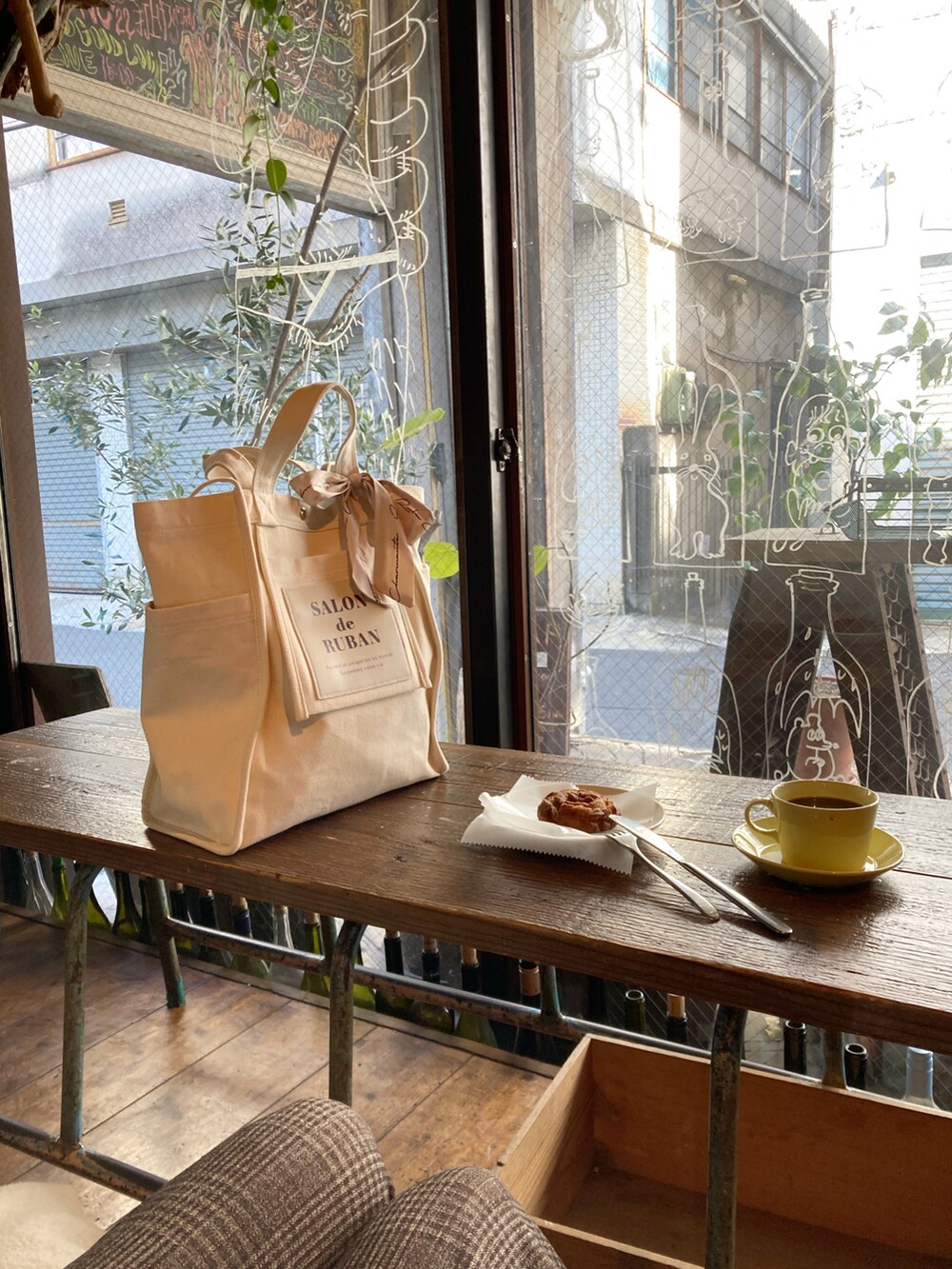 ホワイト系のトートバッグ、ブラック系のブルゾン、ブラウン系のパンツを着用したレディースの冬コーディネートの4枚目の写真