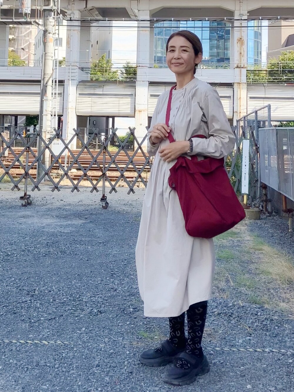 ベージュ系のワンピース/ドレス、レッド系のボストンバッグ、ブラック系のシューズを着用したレディースの秋コーディネートの2枚目の写真