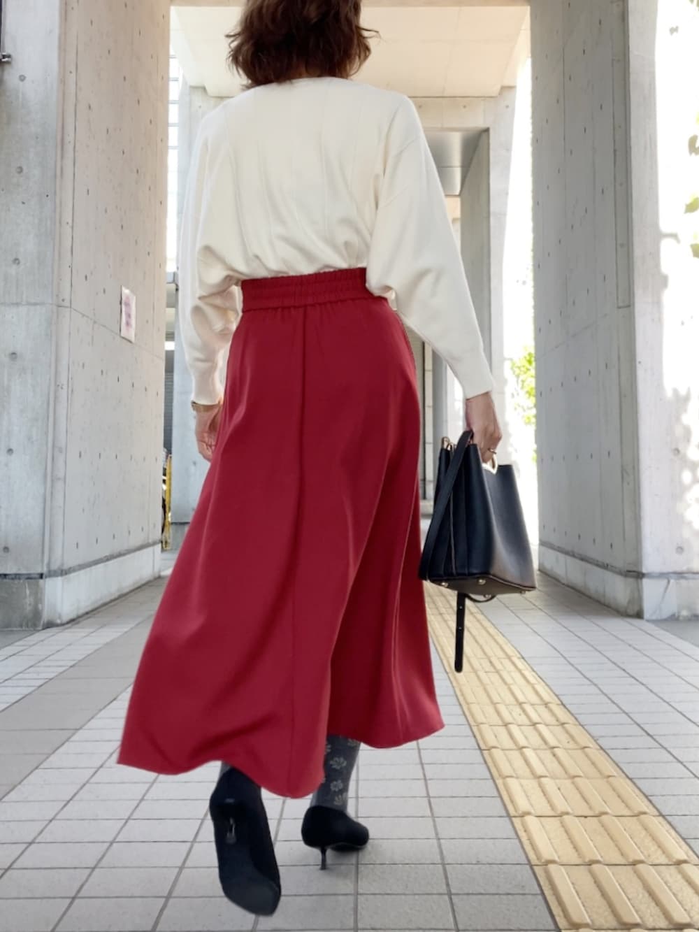 ホワイト系のニット/セーター、レッド系のスカート、ブラック系のハンドバッグを着用したレディースの秋コーディネートの2枚目の写真