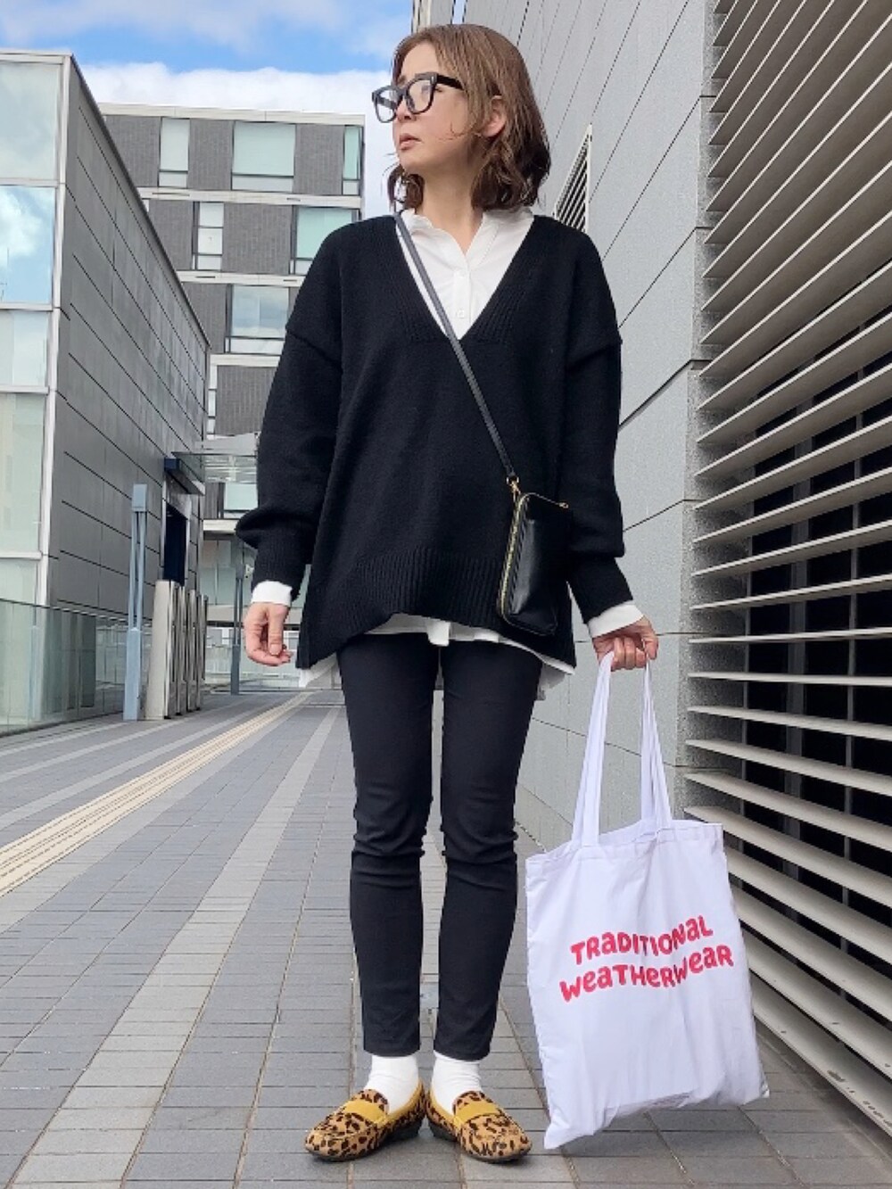 ホワイト系のシャツ/ブラウス、ブラック系のニット/セーター、ブラック系のステンカラーコートを着用したレディースの冬コーディネートの3枚目の写真