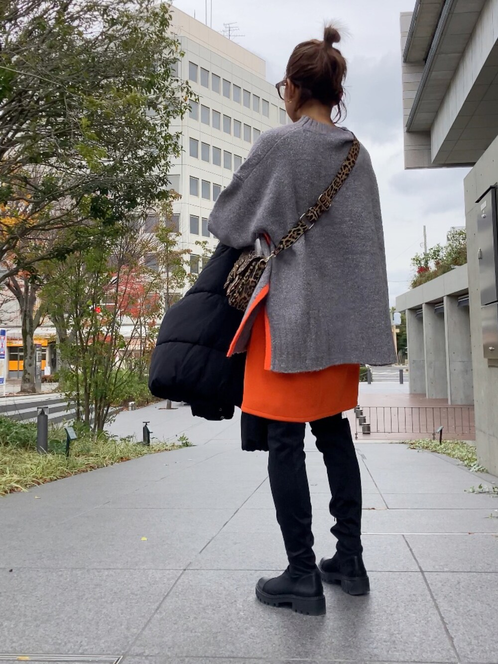 グレー系のニット/セーター、ブラック系のダウンジャケット/コート、オレンジ系のスカートを着用したレディースの冬コーディネートの3枚目の写真