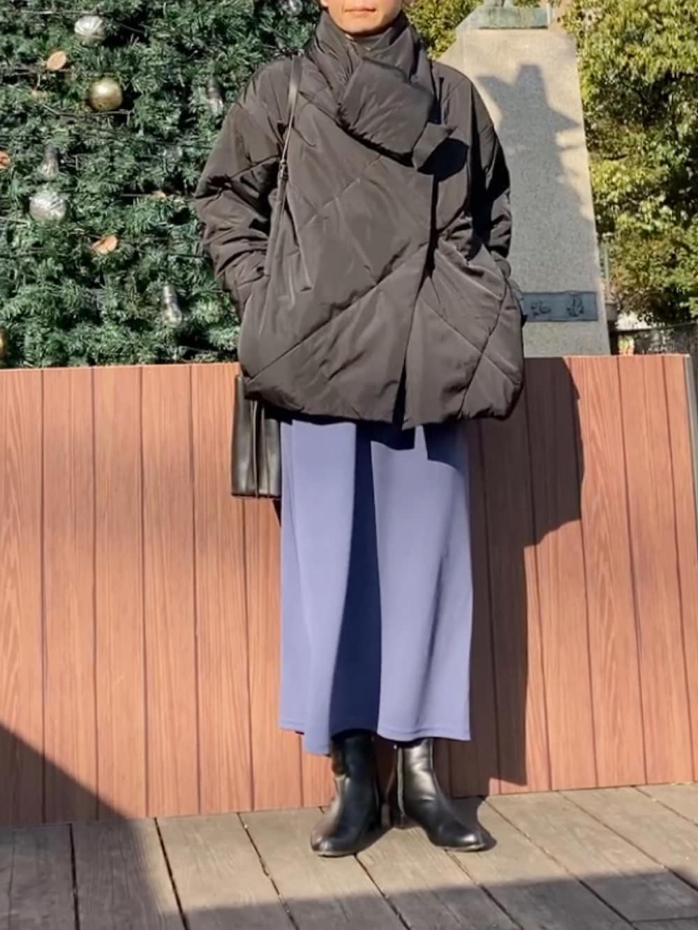 ブラック系のダウンジャケット/コート、ブルー系のワンピース、ブラック系のハンドバッグを着用したレディースの冬コーディネートの4枚目の写真